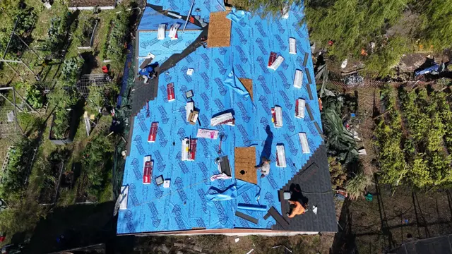 Overhead drone photo with the underlayment fully installed and shingle bundles staged across the roof, ready for installation. Spreading bundles across the slopes before shingling keeps the crew moving efficiently and avoids overloading one area of the roof. Shots like this show the homeowner exactly where the project stands, even if they are at work during the build.