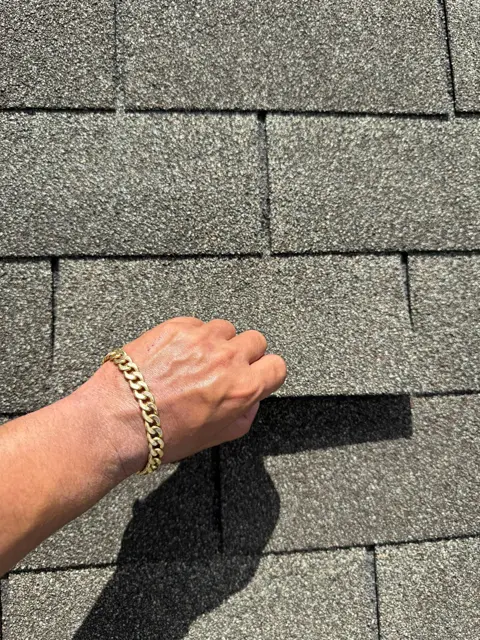 A loose shingle tab lifts freely by hand on the Pearland roof because the adhesive bond failed during high winds. A shingle that moves like this can no longer shed water the way it was designed to, and the repeated flexing cracks the mat over time. Many wind-damaged roofs look fine from the street, which is why a hands-on and drone inspection is the only reliable way to find damage like this after a Houston-area storm.