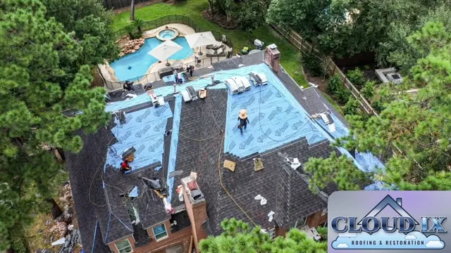 Hail claim reroof in progress on a two-story brick home in Spring, Texas. The old hail-damaged shingles come off section by section while the crew dries in each area with blue synthetic underlayment, so the house is never left open to weather. With tall pines on every side and a pool in the backyard, the tear-off is staged carefully to keep debris contained. Stripping down to the decking lets the crew check the roof deck before the new Class 3 shingles go on.