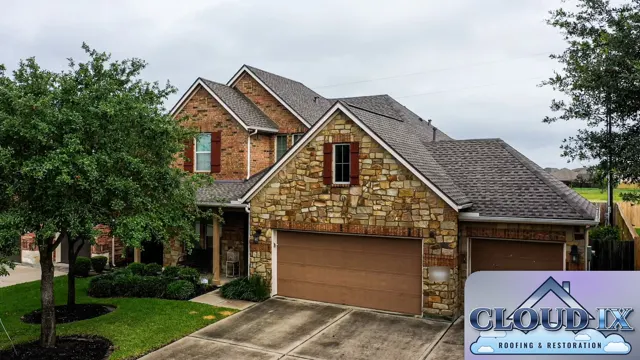 The finished roof on the stone and brick two-story home in The Woodlands after the wind storm, with new brown-gray architectural shingles across the main roof, front gables and garage wing. Wind damage usually starts by breaking shingle seals and lifting tabs, and once that happens the roof keeps getting worse in every storm. A full new roof restores one sealed, uniform surface and the curb appeal of the home.